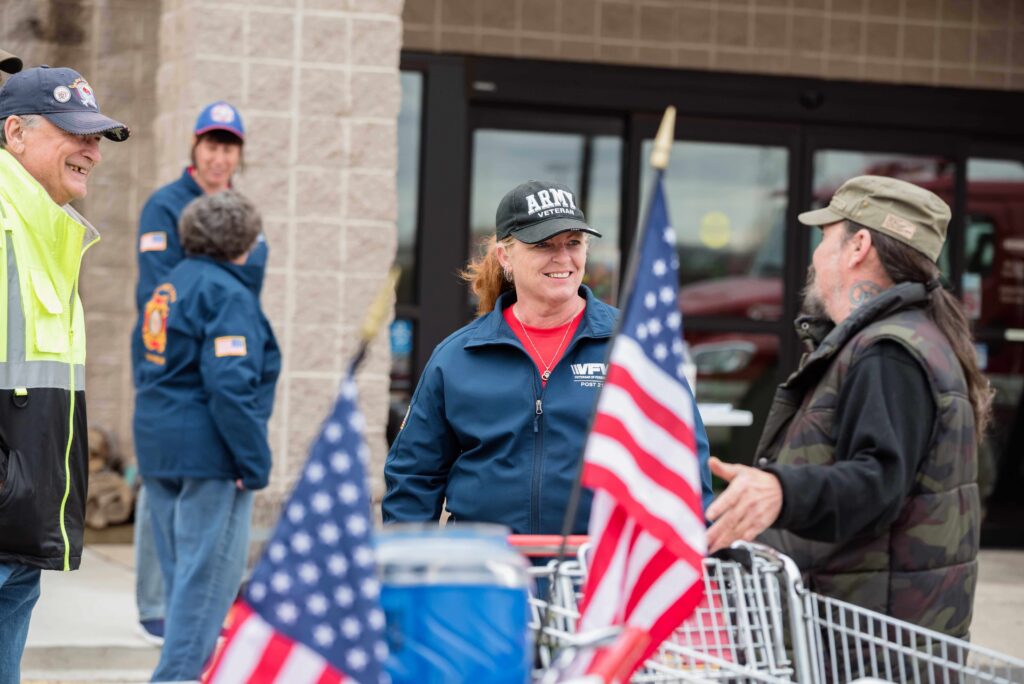 Two women talking with two American flags in front.