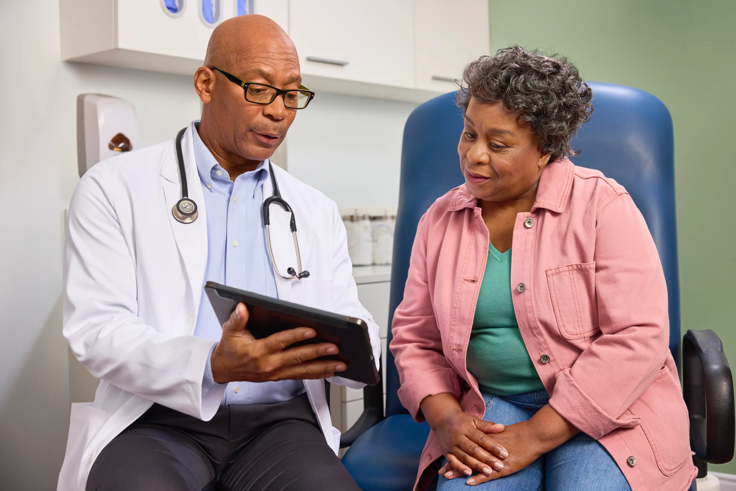Un médico analiza información de salud en una tableta con un paciente en un entorno de consulta médica.