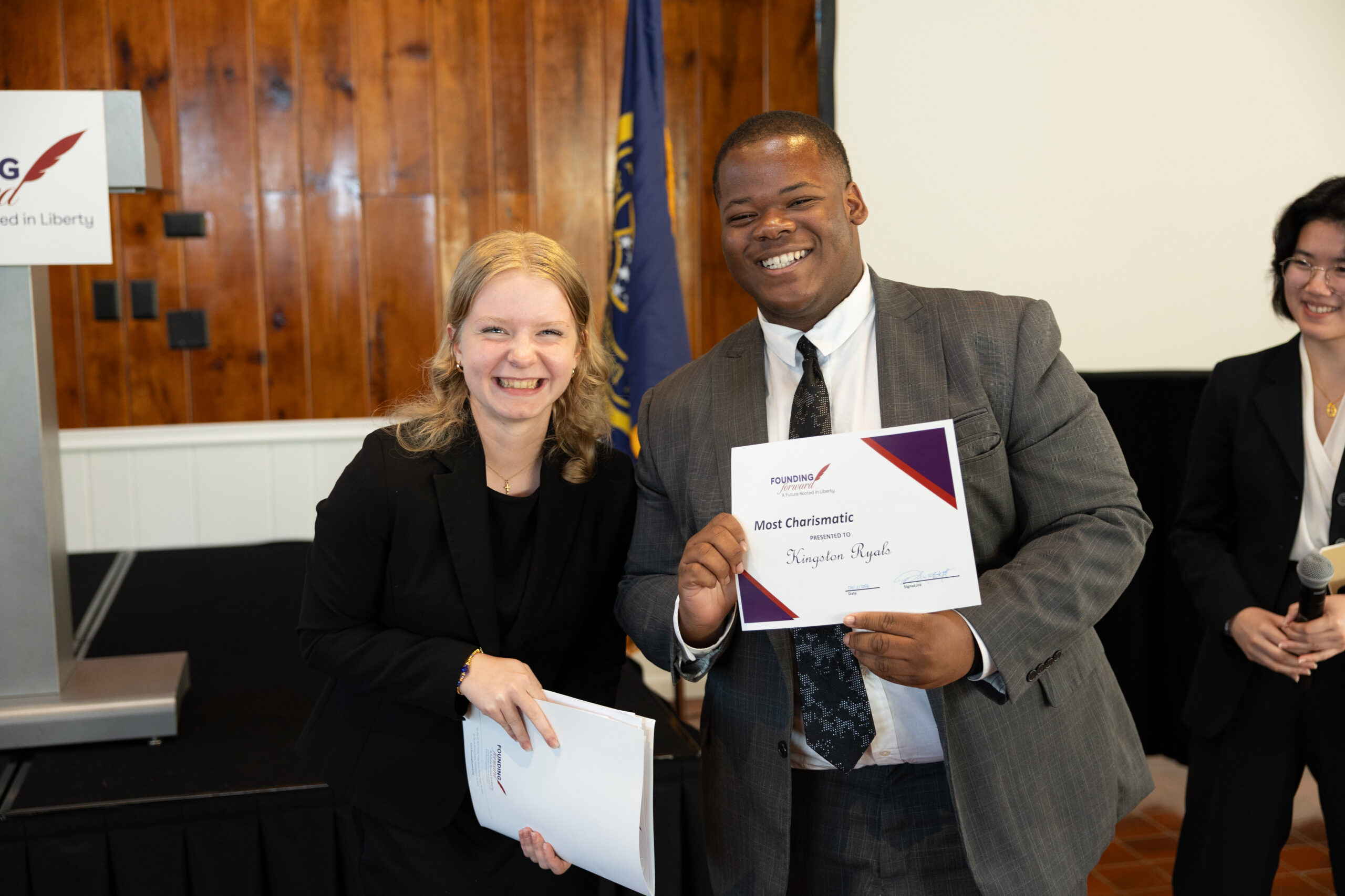 Young man and woman standing next to each other smiling for the picture with certificates in hand.