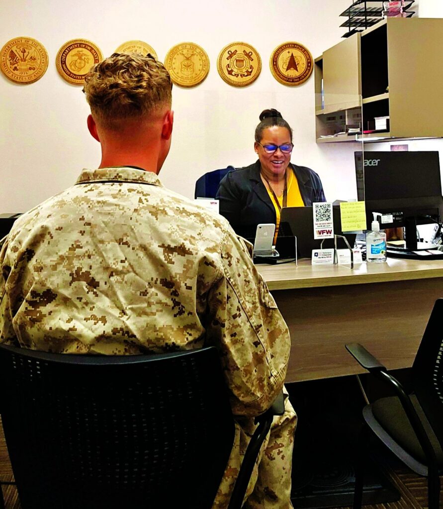 A veteran in military uniform consults with a service representative at a veteran support office.