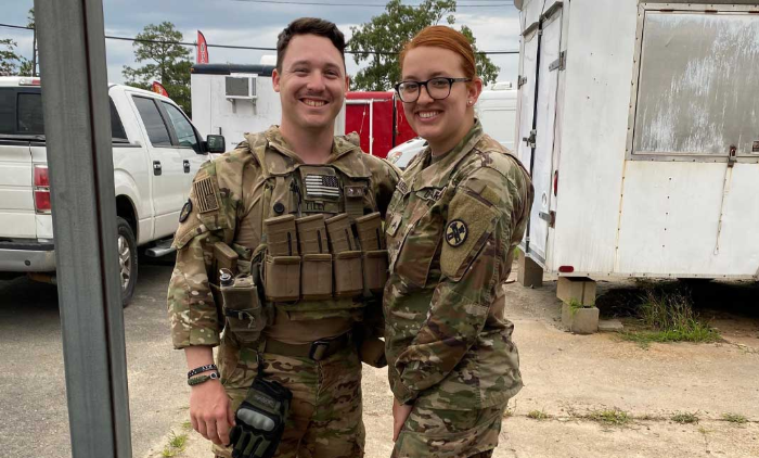 Two military personnel smiling together in uniform, promoting camaraderie and support for the Help a Hero Scholarship.