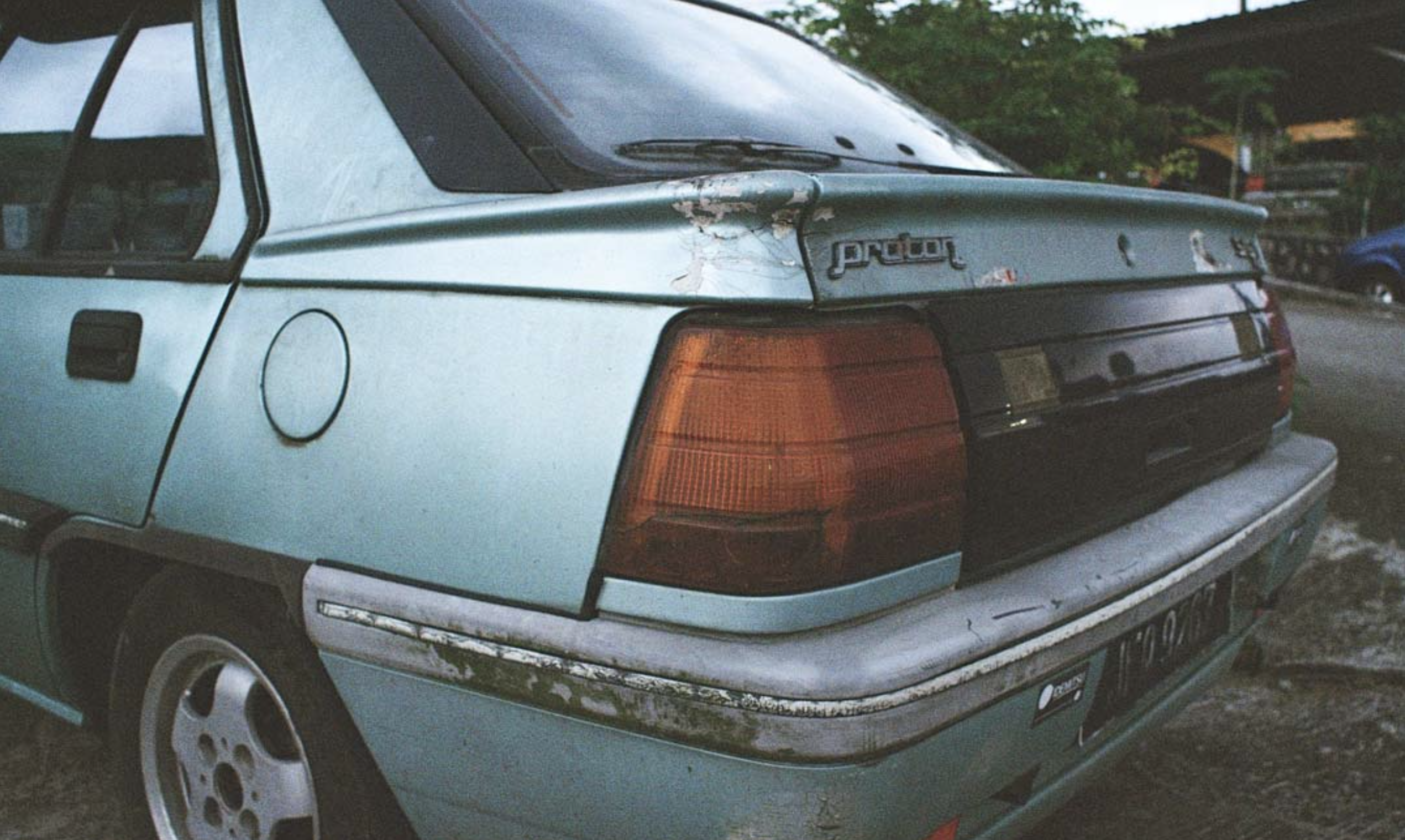 Old, damaged blue car parked outdoors, promoting VFW's vehicle donation program for veterans.